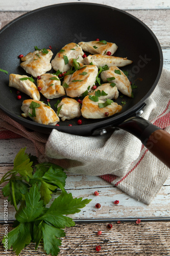 Roasted chicken breast with parsley and red pepper in antique looking frying pan