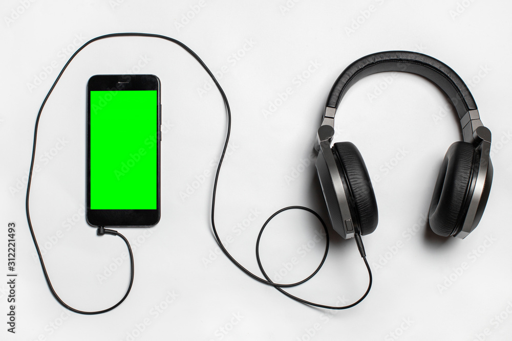 black phone with green screen and headphones on white background, view from above black phone with green screen and headphones on white background, view from above