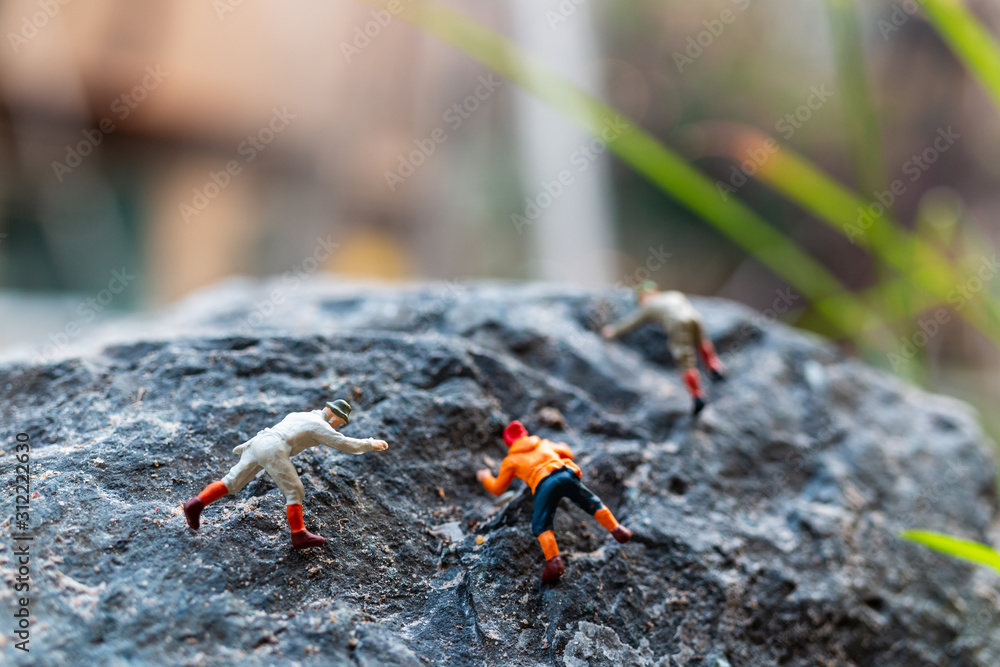 Miniature people: Hikers climbing up on the rock . Sport and leisure concept