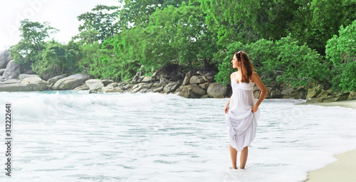 Elegant woman in white dress walking on the beach in Thailand. Holidays, traveling, vacation.