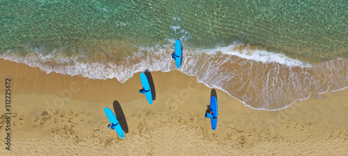 Aerial drone ultra wide photo of surfers practising with their surf boards in tropical exotic sandy bay with turquoise sea