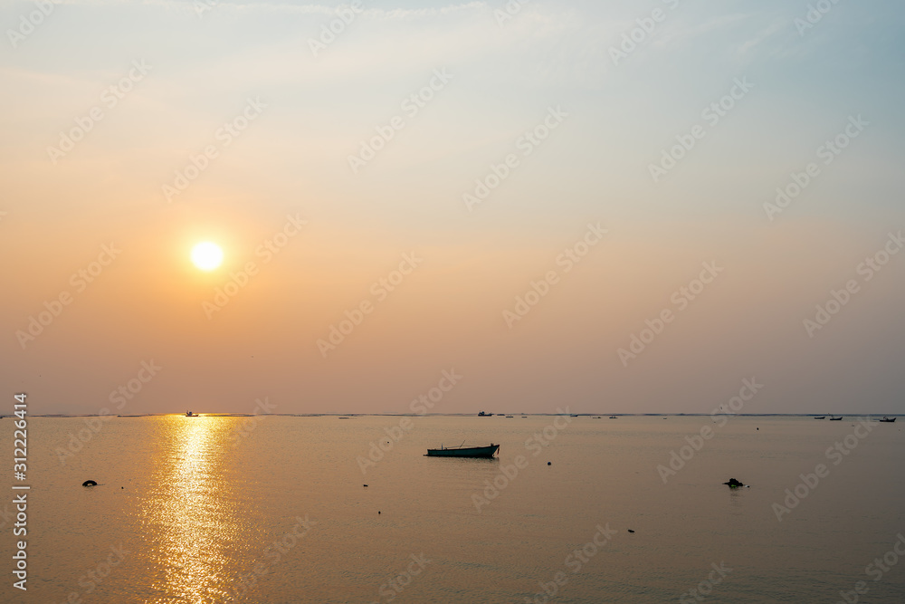 Beautiful seascape sunset with silhouette fishing wood boat floating down on sea in asia