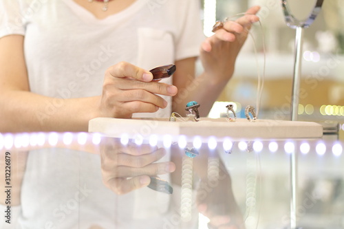Asian short hair woman which is customer choosing and looking for jewellery gift for her special day with happy face. woman wearing beautiful Gems and diamond necklace in jewellery store