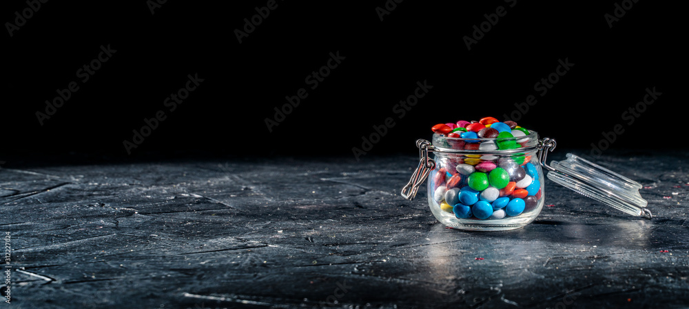 Colorful candies chocolate inside a jar on dark background