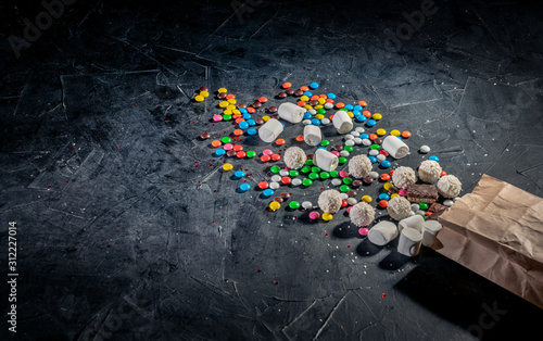 Paper bag of colorful candies on dark background