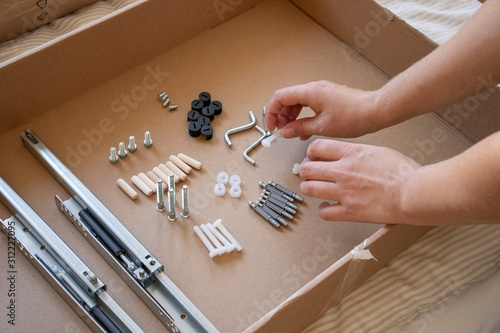 Process of assambling a black drawer of a furniture from sorting pieces to screwing them