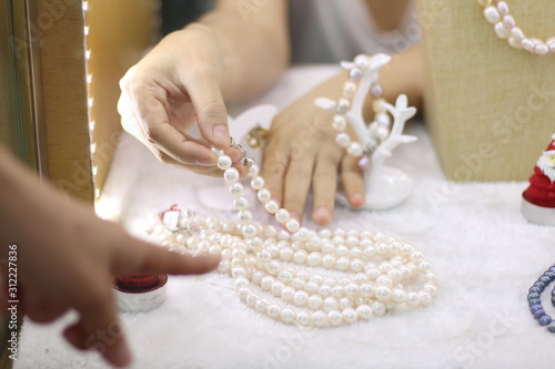 Seller hands decorated natural Pearl necklace in show case of the jewellery shop for customer choose to buy