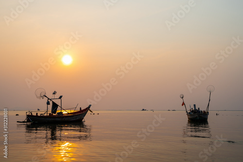 Beautiful seascape sunset with silhouette fishing wood boat floating down or park on sea in asia thailand
