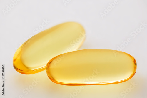 Omega 3 fish oil, two gel capsules macro photo over white background, food supplement for health care. Pharmaceutical industry. Pharmacy.