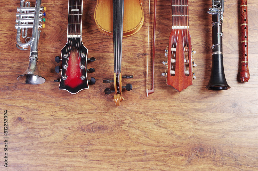 Naklejka premium Musical instruments on a wooden textured background. Block flute, violin, guitar, electric guitar, trumpet