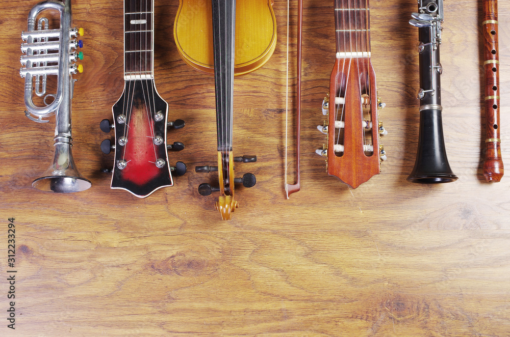 Naklejka premium Musical instruments on a wooden textured background. Block flute, violin, guitar, electric guitar, trumpet
