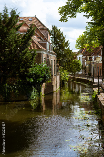 Beautiful and picturesque landscape of the village of Amersfoort, the Netherlands. Typical dutch houses in front of a canal, riverside with trees and flowers. A sunny day. © Malquerida Studio