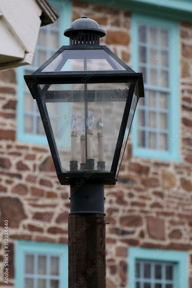 This old fashioned street lamp is in front of the stone house.
