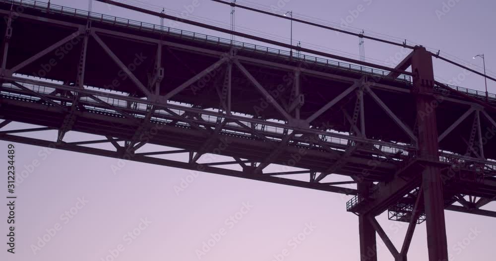 Red suspension bridge shot from the river. Pan shot Red suspension bridge shot from the river. Pan shot