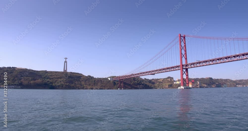 Christ the King and Lisbon bridge shot from a moving boat. River view. Christ the King and Lisbon bridge shot from a moving boat. River view.
