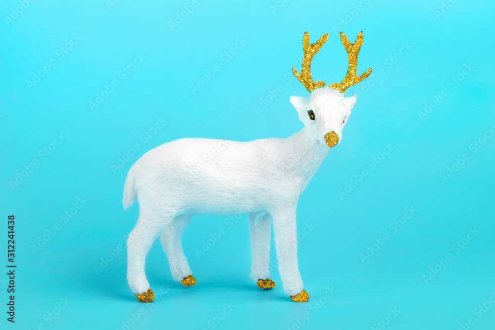 Fototapeta premium white deer decorated with sequin in golden color on blue background. Happy New Year, Merry Christmas concept Holiday card Flat lay Top view Scandinavian style Place for text