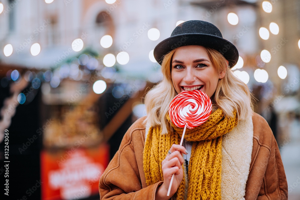 Smiling young woman eating Christmas candy, portrait, copy space.
