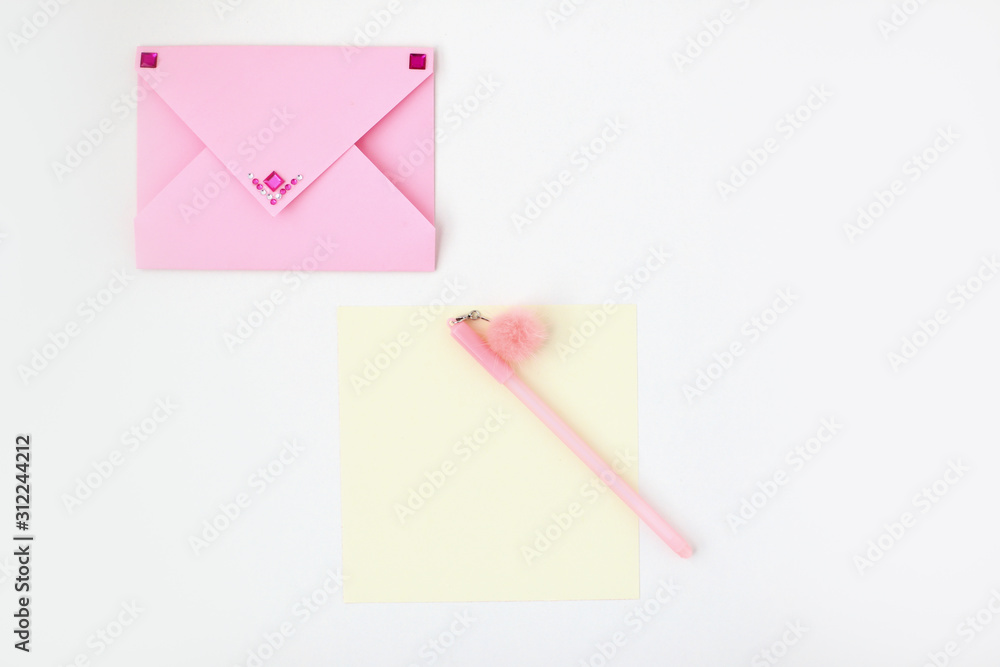 Flat lay: yellow paper, pink envelope with rhinestones, pen with pompom. Making postcard in envelope for Valentine's Day. Do it yourself. Photo from the series