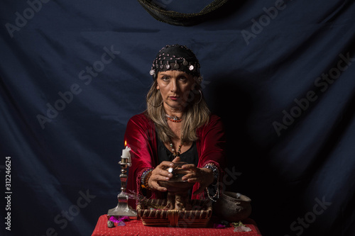 Gypsy fortuneteller or esoteric Oracle wonders on the magic crystal ball photo