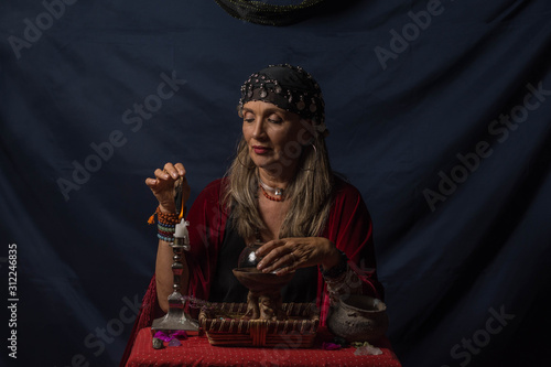 Gypsy fortuneteller or esoteric Oracle holding a smoking piece of wood and a magic crystal ball photo