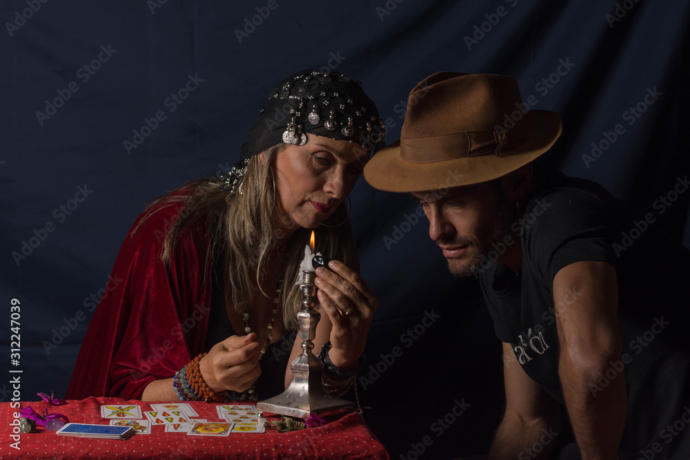 Gypsy fortuneteller or esoteric Oracle holding a stone and read the fortune to a young man with a hat Gypsy fortuneteller or esoteric Oracle holding a stone and read the fortune to a young man with a hat