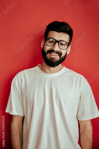 Handsome man standing on red background who is happy