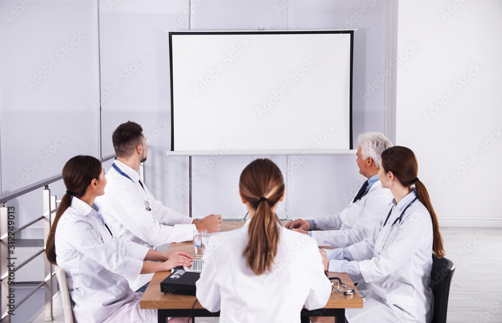 Fototapeta premium Team of doctors using video projector during conference indoors