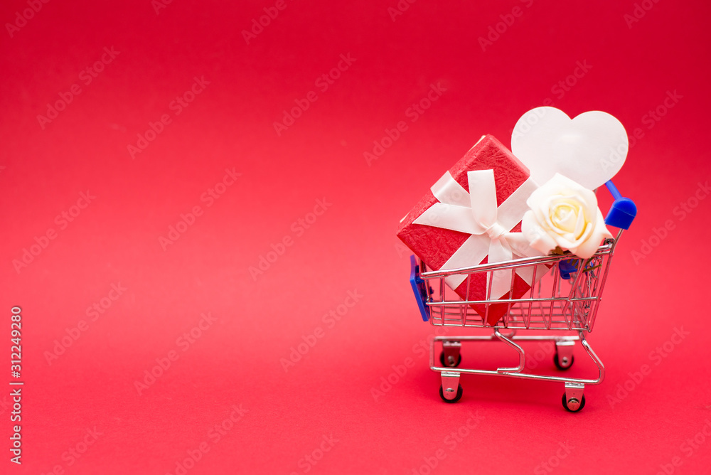 Shopping cart with red gift box and white heart on Red Background. copy space