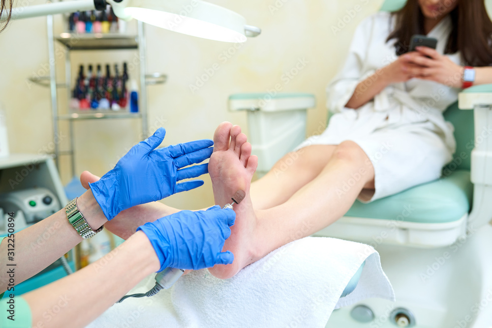 Woman feet receiving pedicure. Beautician doing pedicure. Close up concept.