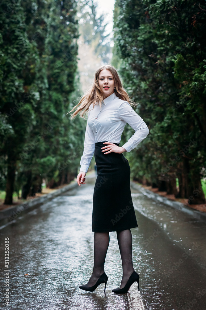 Young business woman in skirt posing outdoors in the rain Young business woman in skirt posing outdoors in the rain