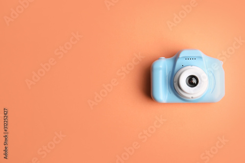 Light blue toy camera on orange background, top view with space for text. Future photographer