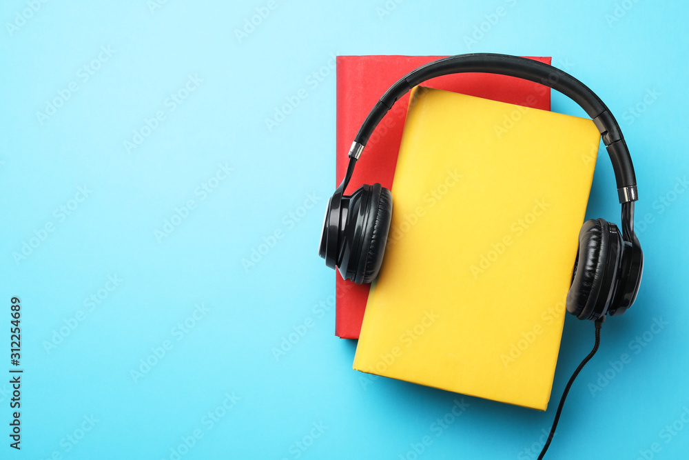 Books and modern headphones on light blue background, top view. Space for text Books and modern headphones on light blue background, top view. Space for text