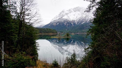 Zugspitze (mountain) in the Alps. Tourism spot. Nice hiking trail around the lake. Fir trees, rock fragments, stones. Zugspitze in background. Insta spot. Reflections in water. Ski region.