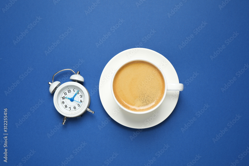 Classic black coffee and alarm clock on blue background, top view. Color of the year 2020 Classic black coffee and alarm clock on blue background, top view. Color of the year 2020