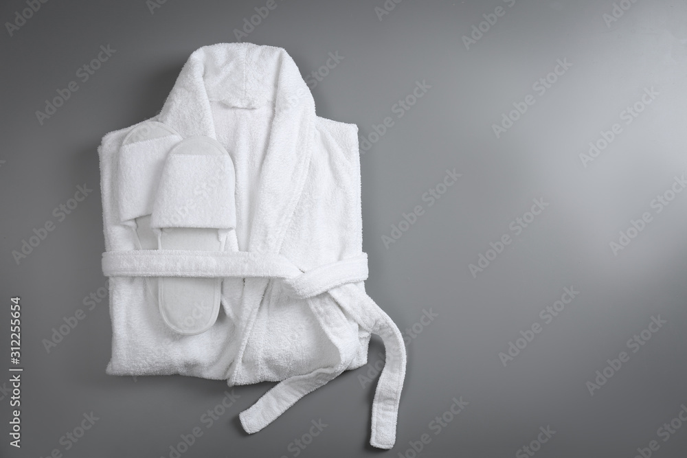 Clean folded bathrobe and slippers on grey background, top view. Space for text Clean folded bathrobe and slippers on grey background, top view. Space for text