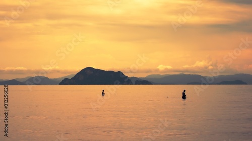 Two fishermen at sunset collecting their catch in Yao Yai island, Thailand.