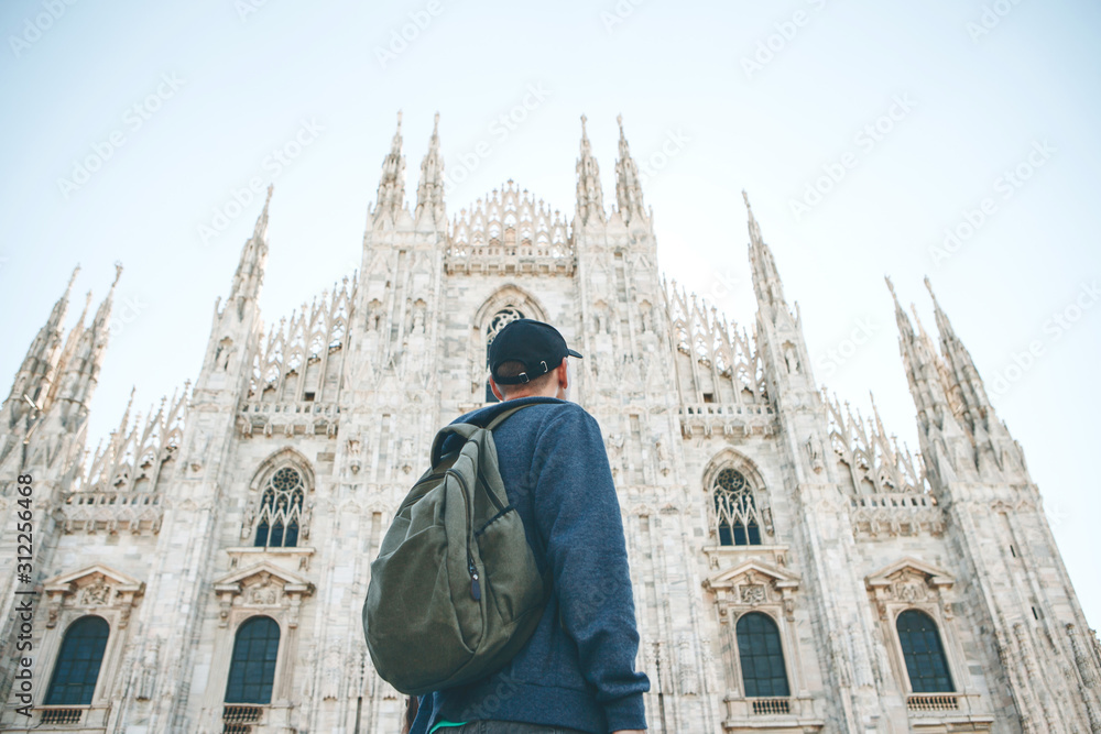 Fototapeta premium Turysta lub student z plecakiem ogląda zabytki Mediolanu we Włoszech. Podziwia katedrę Duomo na rynku miejskim.