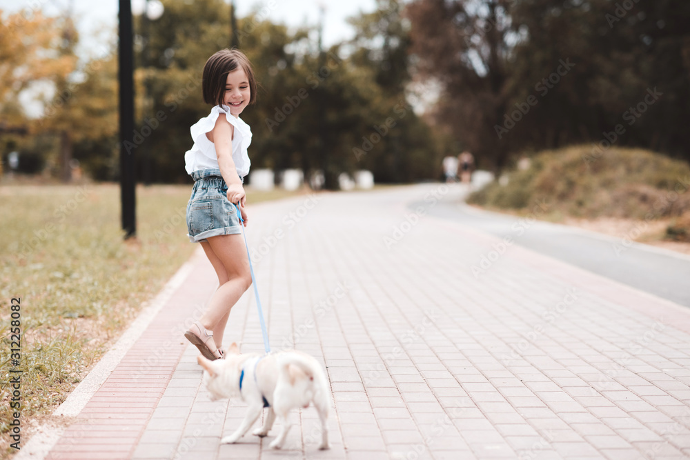 Fototapeta premium Funny baby girl 3-4 year old walking in park with puppy dog outdoors. Summer time. Childhood.
