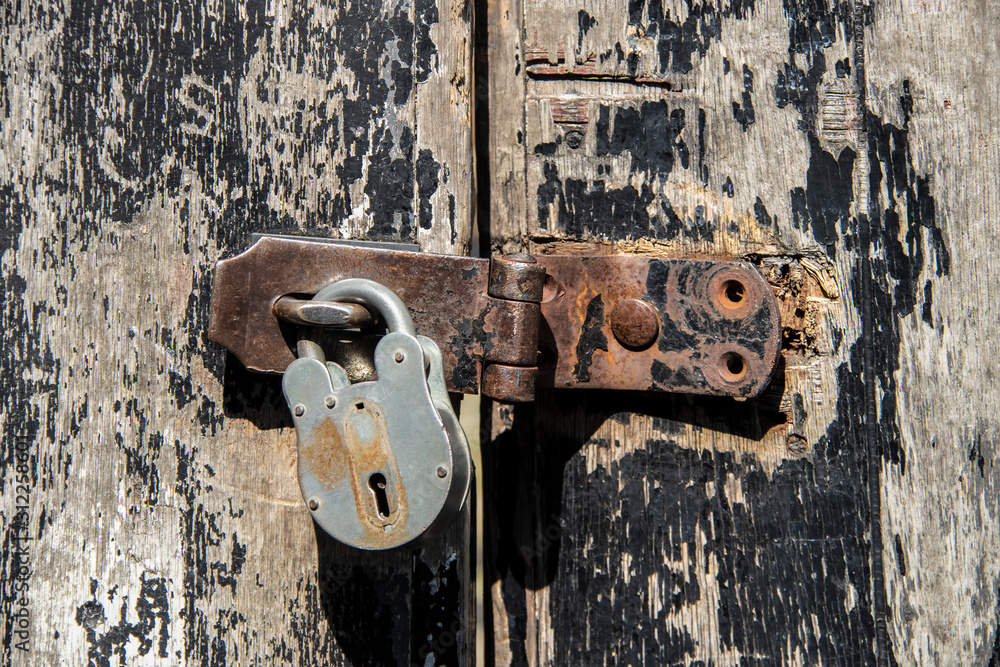 Heavy duty lock on rusty safety hasp on old doors with paint peeling