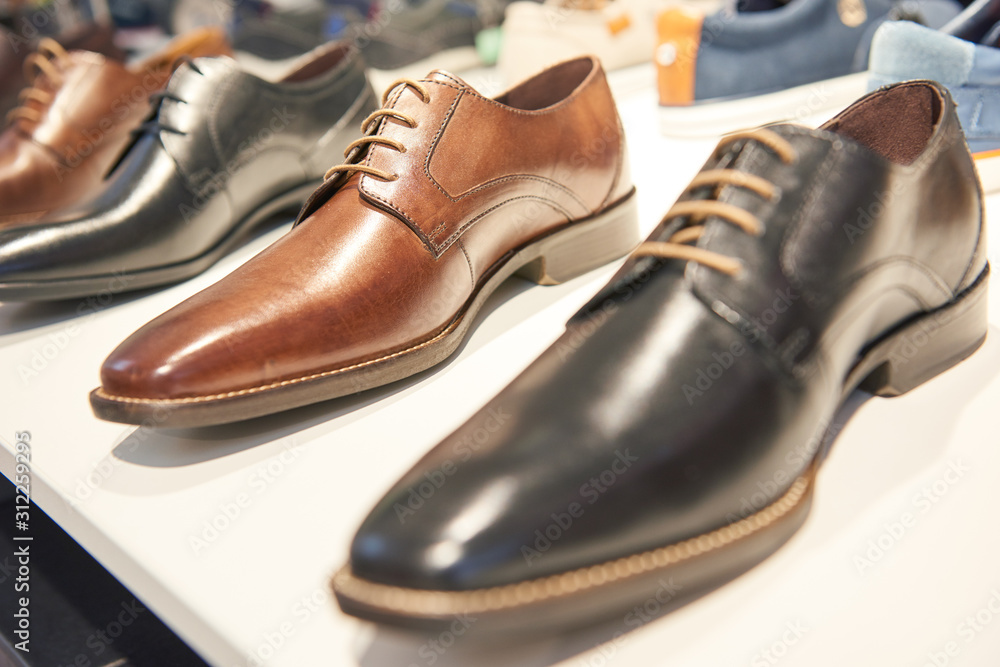 male footwear selling. Formal leather shoes at shelf in shop window - obrazy, fototapety, plakaty 