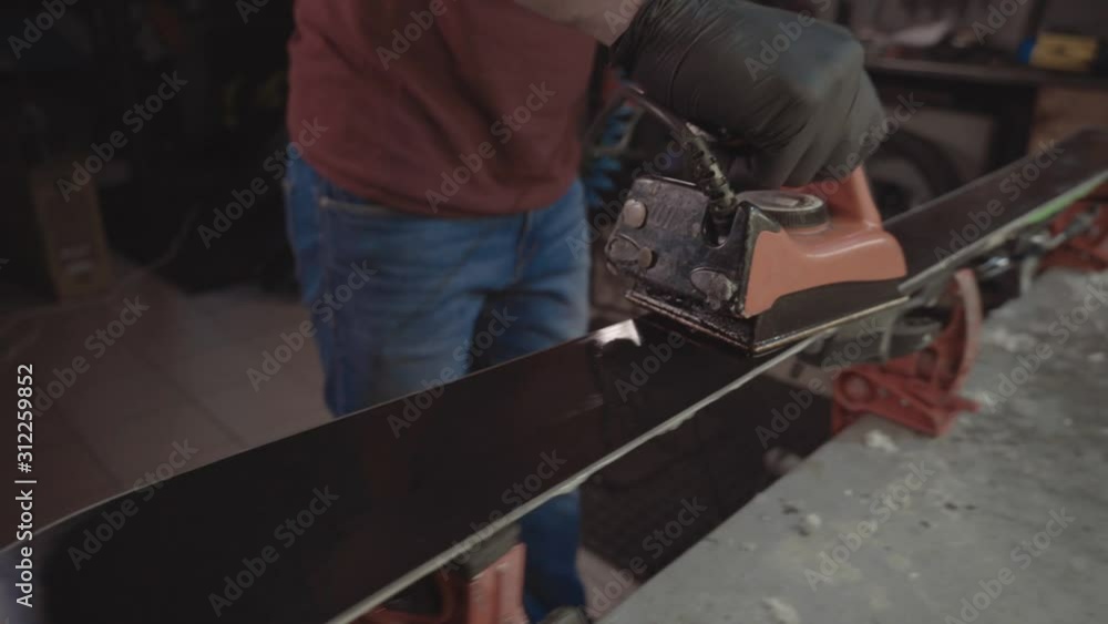 Applying hot wax to ski base with iron. Applying Ski Wax To Ski Base. Ski base tuning. Ski wax iron and wax bars. Ski service and repair. repairman in workshop ski service. Man Waxing Ski In Workshop Applying hot wax to ski base with iron. Applying Ski Wax To Ski Base. Ski base tuning. Ski wax iron and wax bars. Ski service and repair. repairman in workshop ski service. Man Waxing Ski In Workshop