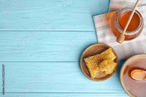 Flat lay composition with delicious honey on blue wooden table. Space for text