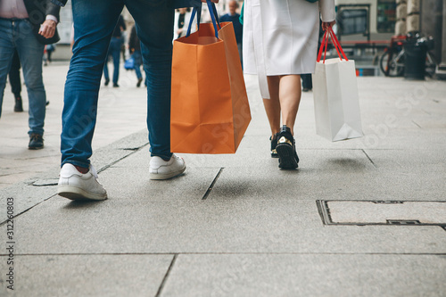 People with bags after shopping walk down the street.