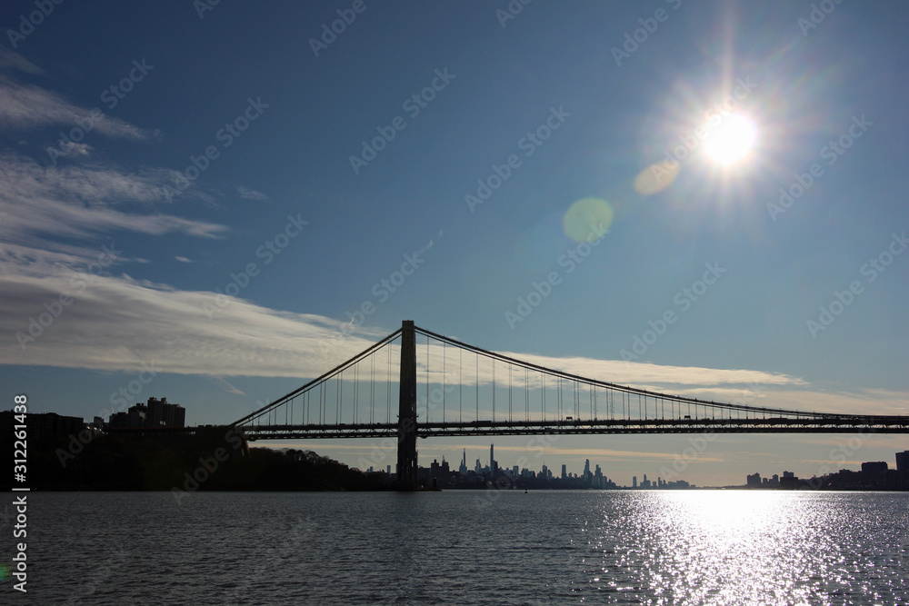 Fototapeta premium George Washington Bridge and Manhattan skyline in backlit view down the Hudson River