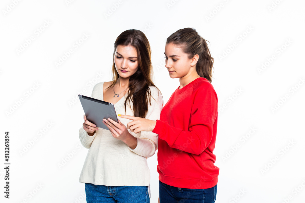 Portrait of a two cute teen girls sharing a tablet computer isolated on white background Portrait of a two cute teen girls sharing a tablet computer isolated on white background