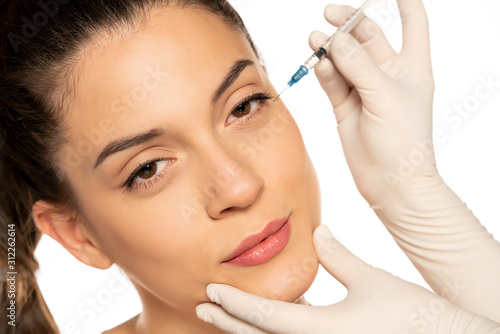 Portrait of a young beautiful woman on a face filler injection procedure on white background