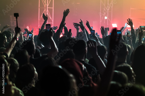  people having fun and dancing with their hands to the sky during a live music concert