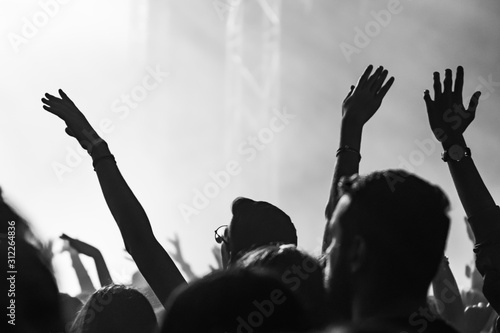  people having fun and dancing with their hands to the sky during a live music concert