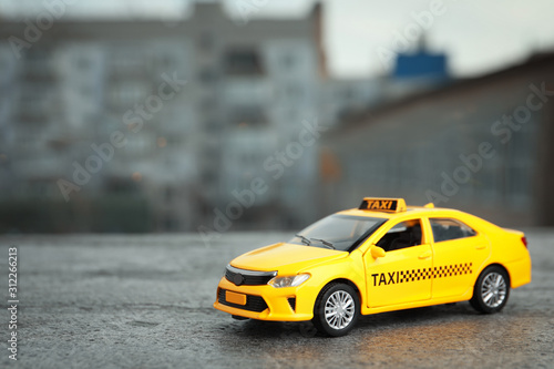 Yellow taxi car model on city street. Space for text