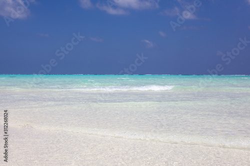 Maldives paradise beach. Perfect tropical island. Moody blue sky and blue lagoon. 